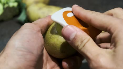 Slowmotion-of-a-man's-hands-peeling-a-potato-with-a-peeler