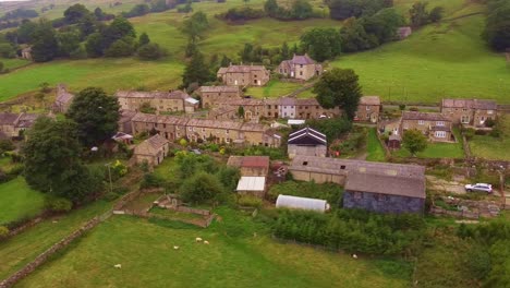 Aerial-shot-rotating-village-in-Yorkshire-Dales-valley-with-patchwork-fields
