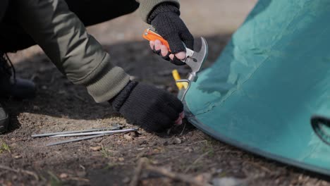 Setting-up-camping-hammering-down-tent-stake-nails-to-ground,-close-up