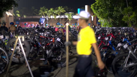 Athletes-gathering-for-a-triathlon-inspecting-their-bikes-early-in-the-morning-at-nighttime-wearing-swimsuits-and-helmets