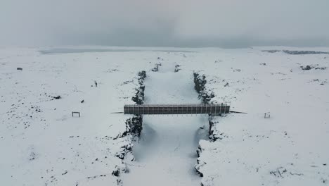 Aerial-View-Of-Bridge-Between-Continents-With-Person-Crossing-During-Winter-In-Reykjanes-Peninsula,-South-Iceland