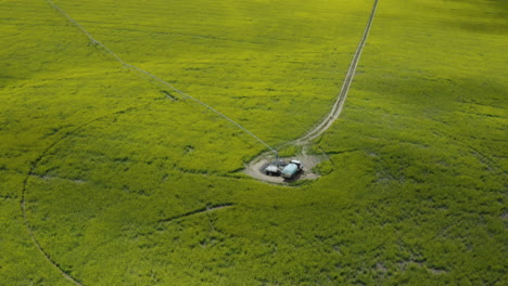 Center-pivot-irrigation-with-tank-truck-in-middle,-green-farm-field,-aerial