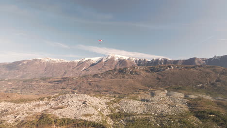 Parapente-Con-Montañas-Cubiertas-De-Nieve-En-El-Fondo-En-Un-Día-Soleado-De-Invierno-En-Trentino,-Italia