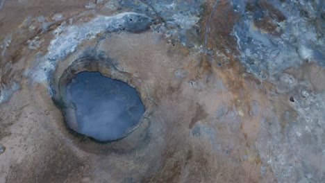 Cinematic-drone-shot-of-blue-colored-boiling-lake-in-geological-landscape-in-Iceland---Hverir-is-a-geothermal-area