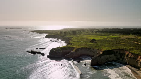 Año-Nuevo-State-Park-California-Aerial-V1-Flyover-Cove-Beach-Fängt-Golden-Schimmerndes-Sonnenlicht-Ein,-Das-Auf-Das-Meerwasser-Und-Die-Ozeanische-Felsklippenlandschaft-Scheint-–-Aufgenommen-Mit-Mavic-3-Cine-–-Mai-2022