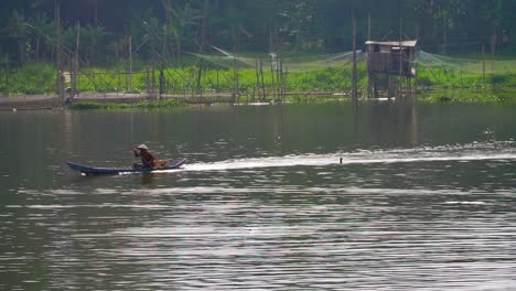 Fisherman-is-crossing-lake-with-traditional-boat-in-Rawa-Pening-lake,-Indonesia