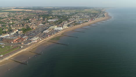 High-Establishing-Aerial-Drone-Shot-Flying-Over-Coastal-Seaside-Town-New-Hunstanton-with-Groynes-along-Sandy-Beach-and-Ferris-Wheel-and-Fun-Fair-with-Calm-Sea-with-Small-Waves-North-Norfolk-UK