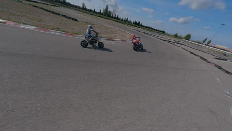 Action-FPV-drone-POV-following-motorcycle-riders-turning-through-racetrack-corners,-Aerial-view