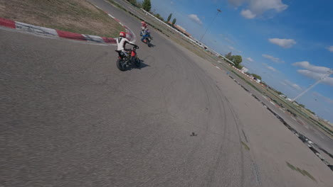 Dynamic-FPV-drone-pursuit-through-motorcycle-riders-on-racetrack-lap-corners,-Aerial-view