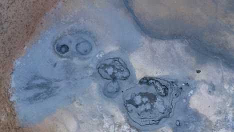 Aerial-top-down-:-Icelandic-blue-colored-boiling-mud-pools-in-volcanic-crater-landscape-of-Iceland---Phenomenal-aerial-of-natural-sulfuric-steam-rising-up-into-air