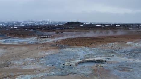Low-altitude-flight-over-boiling-field-of-geothermal-mud-pools-and-landscape-in-Iceland