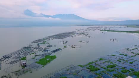 Aerial-view-of-fish-cages-on-lake-in-Indonesia-with-mountains-in-background