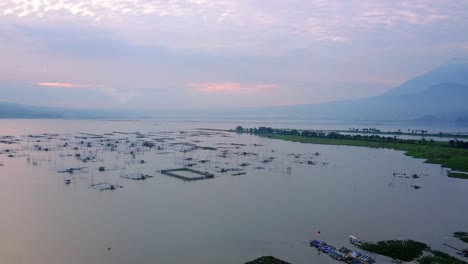 Aerial-panorama-view-of-lake-with-fishing-farms-during-purple-sunrise-behind-cloudscape-in-Indonesia