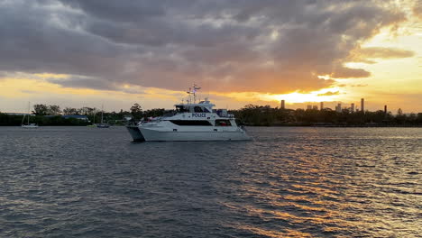 Queensland-Water-Police-Vessel-Patrols-Brisbane-River-With-Orange-Sunset-In-The-Background