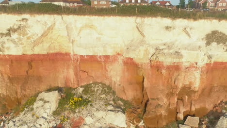 Pullback-Aerial-Drone-Shot-from-Closeup-of-Old-Hunstanton-Orange-and-White-Cliffs-with-Small-Sandy-and-Rocky-Beach-North-Norfolk-UK