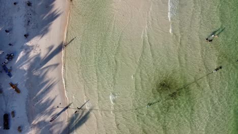 Aerial-Topdown-view-of-translucent-emerald-beach-shore-with-tourists,-Vietnam