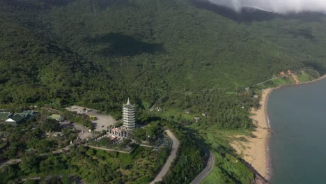 Vista-Aérea-De-La-Estatua-De-Buda-De-Dama-Alta-Y-La-Torre-Del-Templo-Con-Enormes-Montañas,-Impresionante-Costa-Y-Océano-En-Da-Nang,-Vietnam