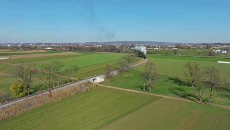 Drone-View-of-a-Steam-Passenger-Train-Rounding-a-Curve-Blowing-Smoke-and-Steam-on-a-Sunny-Fall-Day