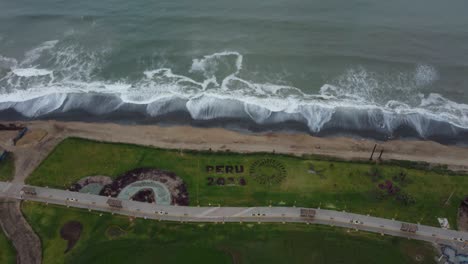 Early-morning-video-of-a-park-in-Lima,-Peru-called-"Bosque-del-Bicentenario"-Drone-flies-back-while-tilting-camera-gimbal-upwards,-showing-the-pacific-ocean-shore-waves