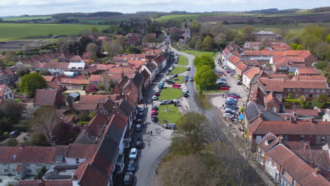 Aerial-Drone-Shot-Flying-Down-Beautiful-Old-Village-Burnham-Market-Main-Street-Towards-St-Mary's-Church-on-Sunny-and-Cloudy-Day-in-North-Norfolk-UK
