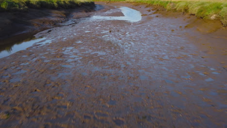 Very-Low-Aerial-Drone-Shot-Flying-Over-Green-Salt-Marsh-at-Low-Tide-Revealing-Whole-Salt-Marsh-in-North-Norfolk-UK