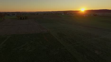 Drohnenansicht,-Die-Sich-Von-Links-Nach-Rechts-Von-Einem-Morgensonnenaufgang-Bewegt-Und-An-Einem-Herbstmorgen-über-Ländliche-Ackerflächen-Blickt