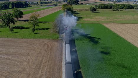 An-Aerial-View-From-Directly-Above-a-Steam-Train-Blowing-Smoke-and-Steam-at-the-Drone-as-it-Travels-Thru-the-Countryside