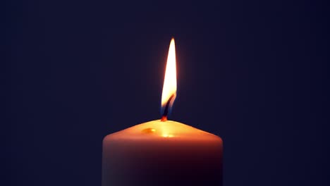 Single-big-yellow-candle-flame-lights-and-extinguish,-isolated-on-a-black-background