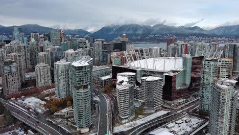 Downtown-Vancouver-British-Columbia-Canada-in-a-Gloomy-and-Snowy-Winter-Day-with-Buildings,-Mountains,-Water,-Streets-and-Cars