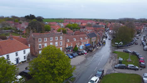 Aerial-Drone-Shot-Flying-Through-Beautiful-Old-Village-Burnham-Market-with-People-Walking-in-Street-Shopping-on-Sunny-and-Cloudy-Day-North-Norfolk-UK