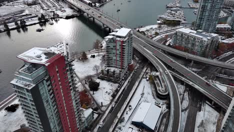Downtown-Vancouver-British-Columbia-Canada-in-a-Gloomy-and-Snowy-Winter-Day-with-Buildings,-Mountains,-Water,-Streets,-Bridge-and-Cars