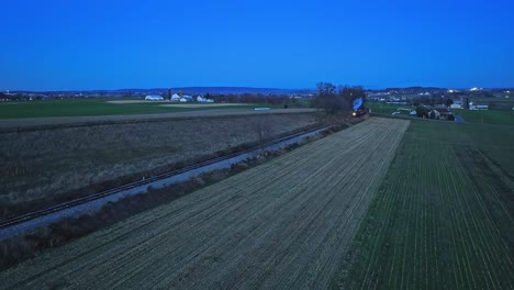 A-Drone-Night-View-of-a-Steam-Passenger-Train-Approaching-on-a-Single-Track-Traveling-Thru-Farmlands