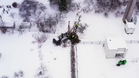 Electric-company-replaces-old-electricity-pole-in-winter,-aerial-view
