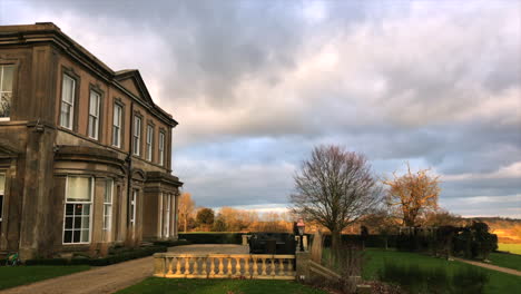 Grand-Leicestershire-Manor-House-Seitenansicht-Mit-Wolken,-Die-Vorbei-Und-über-Hof-Und-Gärten-Wehen
