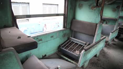 Broken-seat-inside-an-abandoned-train-pan-to-an-empty-hallway