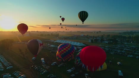 Aerial-view-of-a-hot-air-balloon-festival-early-morning-take-off-into-the-sun-on-a-sunny-summer-day-in-Pennsylvania-countryside
