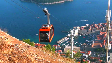 EDITORIAL:-Cable-car-ascending-over-the-walled-medieval-city-of-Dubrovnik,-Croatia-in-2015-with-the-Adriatic-Sea-and-Lokram-Island-in-the-background