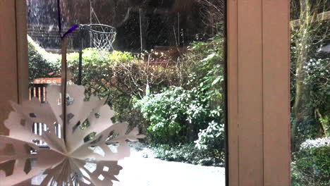 Snow-falling-past-Christmas-snowflake-decoration-into-backgarden-with-netball-hoop