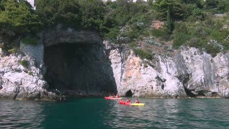 Paddling-kayaks-at-the-foot-of-cliffs-in-Dubrovnik,-Croatia