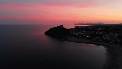 Criccieth-deep-pink-sunset-over-11th-century-castle---Pearl-of-Wales-on-the-Shores-of-Snowdonia---aerial-drone-looking-North-towards-Cardigan-Bay,-Gwynedd,-North-Wales---4K-23