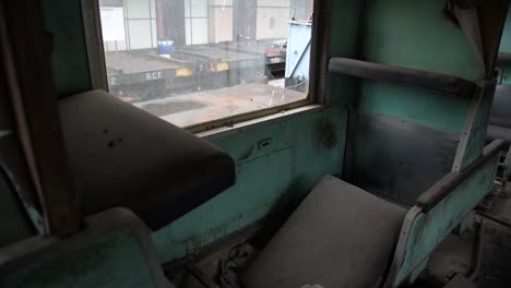 Broken-passenger-seats-inside-an-abandoned-train-with-shattered-window