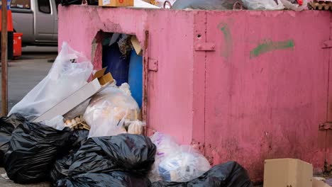 Overflowing-Trash-Dumpster-Inner-City-Street,-TILT-DOWN
