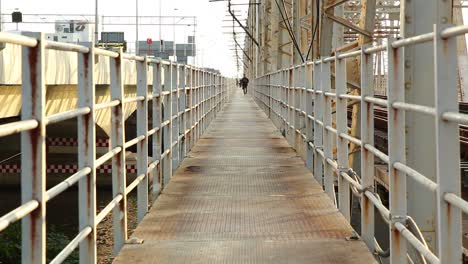 Old-rusty-metal-footbridge-with-a-man-running-in-the-distance