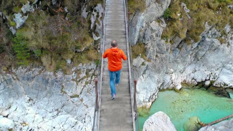 A-hiker-walking-on-a-rope-bridge-on-the-river-Soca,-Triglavski-national-park,-Slovenia