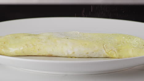 salting-an-egg-omelette-on-a-white-plate