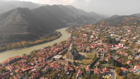 Aerial-video-flying-above-a-church-in-the-city-of-Mtskheta-in-Georgia-with-beautiful-mountains-and-river