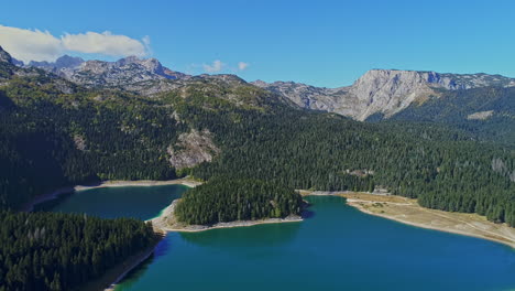 Aerial-view-of-lakes-between-the-mountains-surrounded-by-pine-forests-and-beautiful-blue-sky-with-clouds