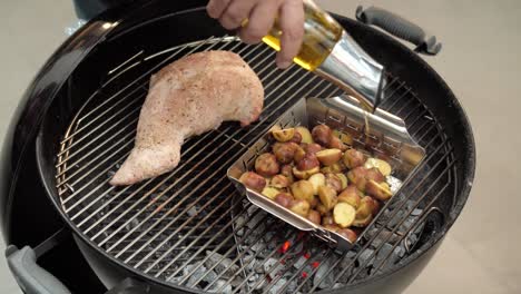 Chef-drizzling-olive-oil-over-potatoes-on-a-hot-grill-with-pork-beef