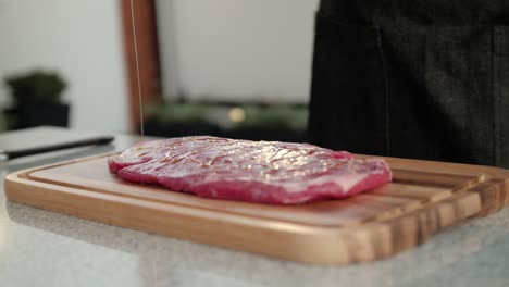 Chef-drizzling-olive-oil-over-beef-steak,-slow-motion