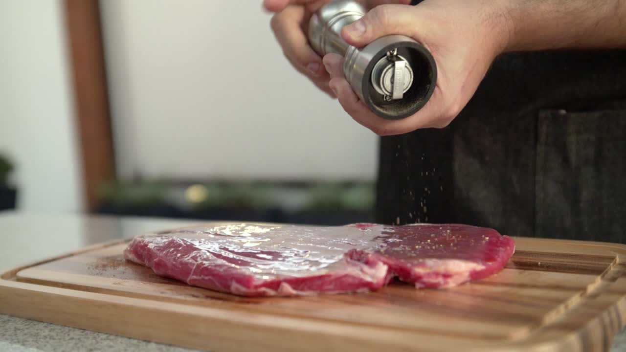 Premium Stock Video Closeup Of A Chef Adding Pepper To A Raw Beef Steak Slow Motion 